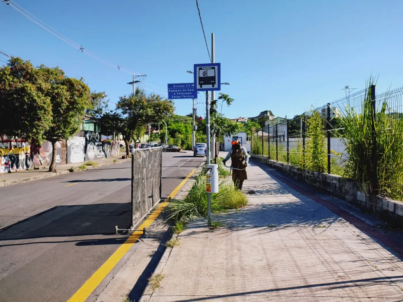 Colaborador da Pequi roçando vegetação em ciclovia urbana com roçadeira costal